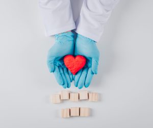 Heart inside the male hands with wooden elements top view on a white background space for text